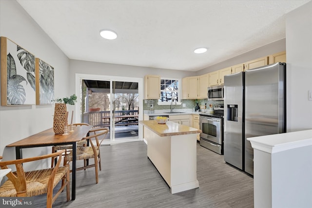 kitchen featuring cream cabinetry, a sink, backsplash, stainless steel appliances, and light countertops