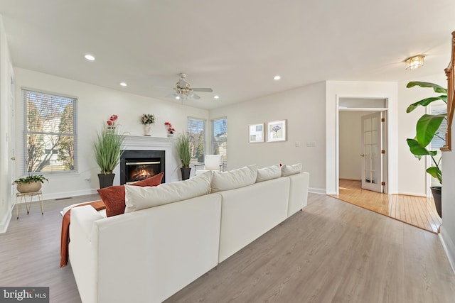 living room with a glass covered fireplace, recessed lighting, and light wood-style floors