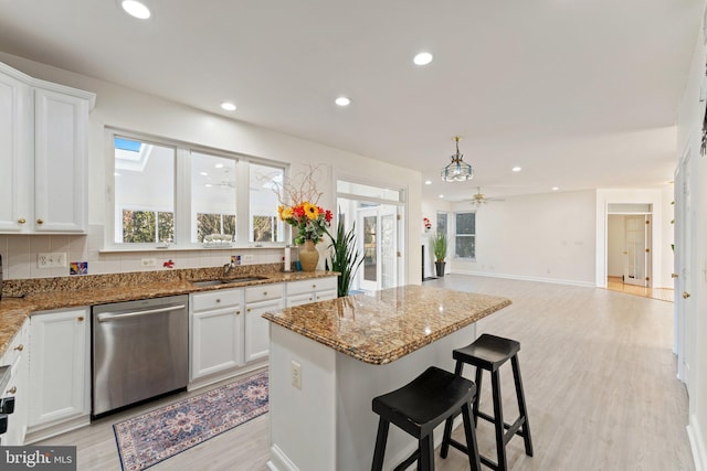 kitchen with white cabinetry, a kitchen island, recessed lighting, stone countertops, and stainless steel dishwasher