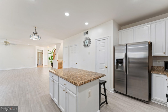 kitchen featuring visible vents, a kitchen island, stainless steel appliances, white cabinets, and light wood-style floors