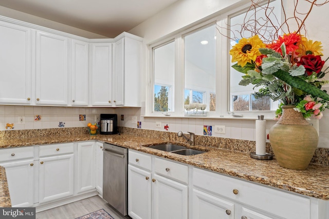 kitchen featuring decorative backsplash, white cabinets, light stone counters, and a sink