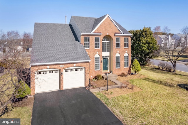 view of front of home with brick siding, an attached garage, a shingled roof, a front lawn, and driveway