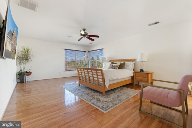 bedroom featuring a ceiling fan, wood finished floors, visible vents, and baseboards