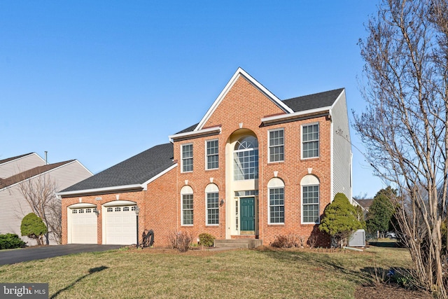 view of front of property with brick siding, an attached garage, a front yard, roof with shingles, and driveway