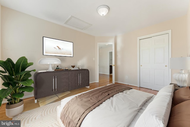 bedroom with baseboards, attic access, and wood finished floors