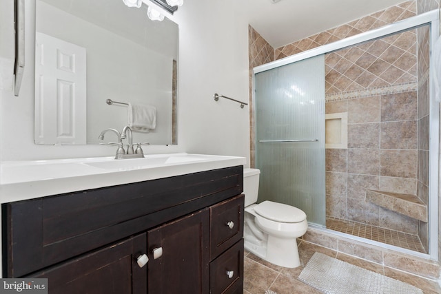 bathroom with tile patterned floors, a shower stall, toilet, and vanity