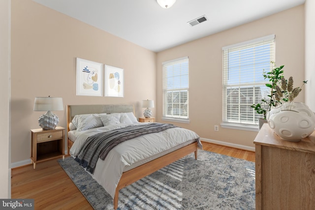 bedroom featuring light wood-type flooring, visible vents, and multiple windows