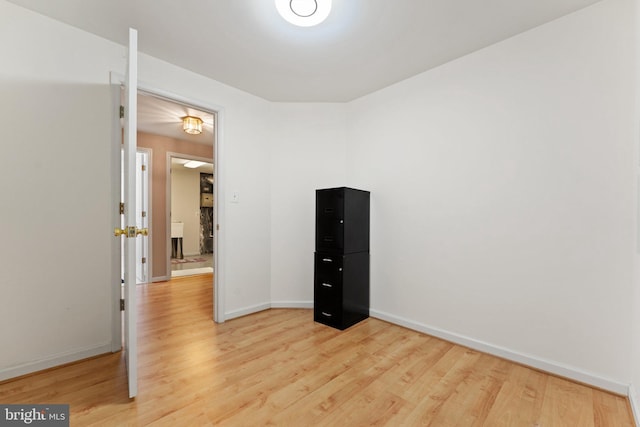 spare room with baseboards and light wood-style flooring