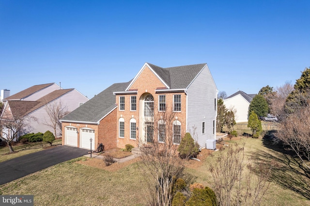 view of front facade with a front yard, a garage, brick siding, and driveway