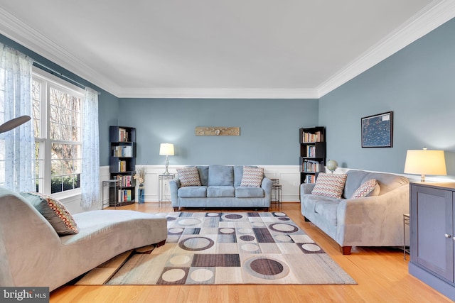 living room with light wood-style flooring, ornamental molding, and wainscoting