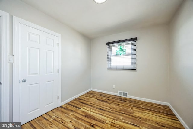 spare room with visible vents, baseboards, and wood finished floors