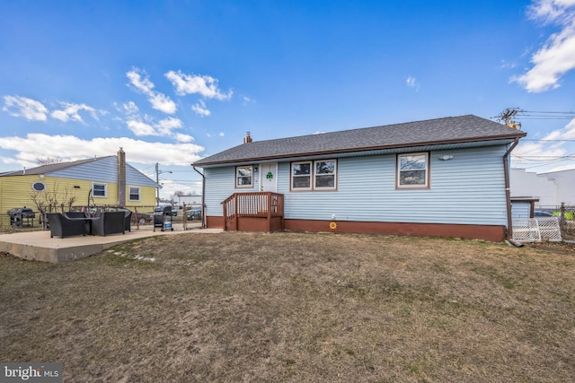 rear view of house with a yard, a patio, roof with shingles, and fence