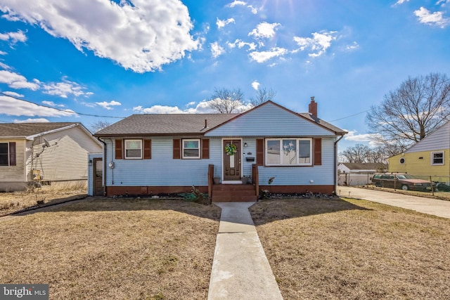 view of front of home with a chimney, a front yard, and fence