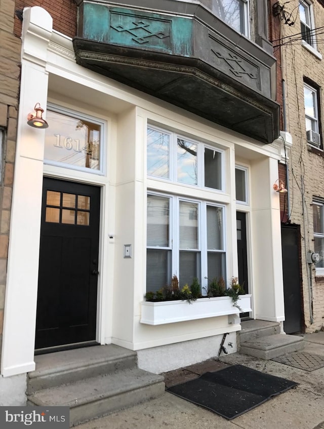 doorway to property with stucco siding and brick siding