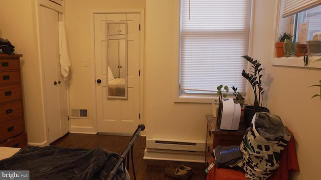 bedroom with dark wood finished floors, baseboard heating, and visible vents