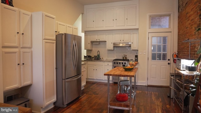 kitchen featuring a sink, white cabinets, under cabinet range hood, appliances with stainless steel finishes, and backsplash