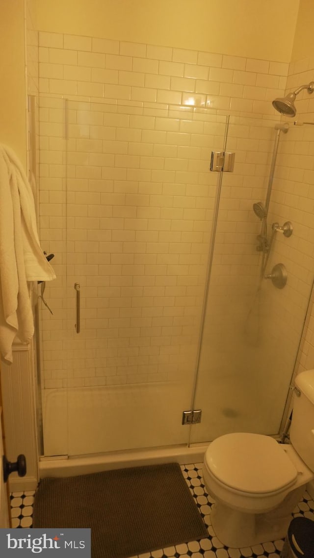 bathroom featuring toilet, a shower stall, and tile patterned flooring