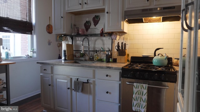 kitchen with stainless steel range with gas cooktop, a sink, decorative backsplash, white cabinets, and under cabinet range hood