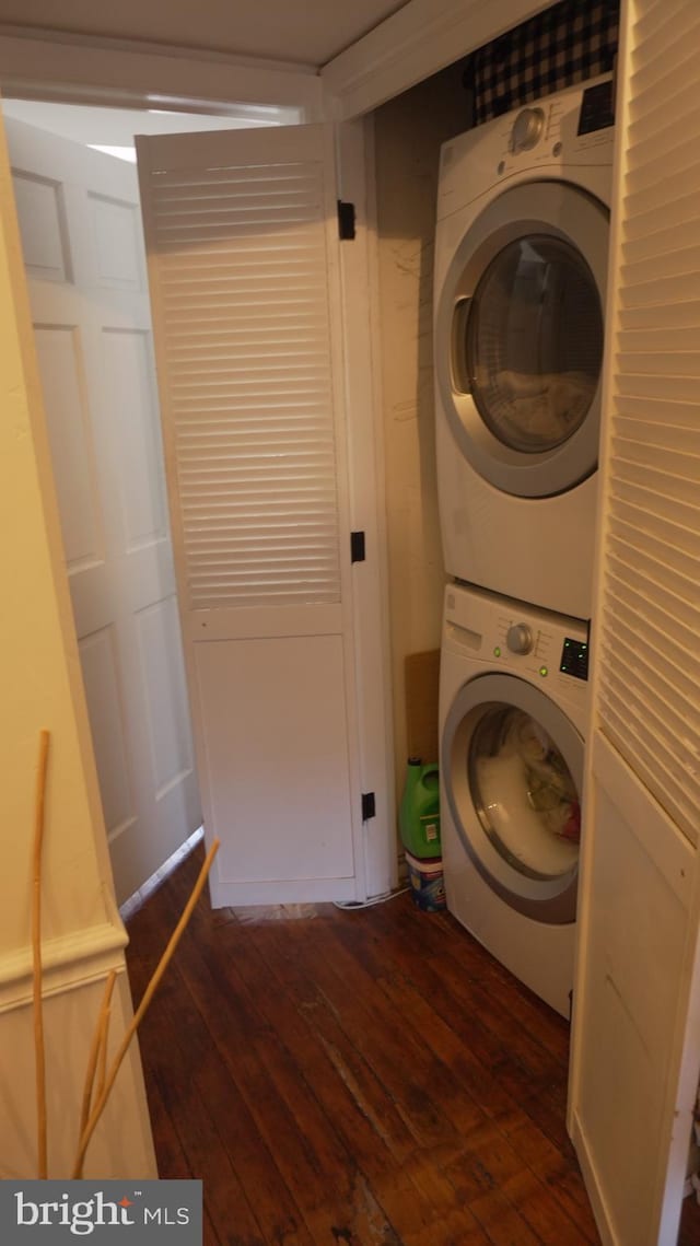 laundry room with dark wood finished floors, laundry area, and stacked washer and clothes dryer