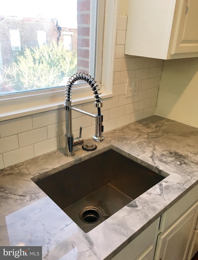 interior details with light stone counters, tasteful backsplash, and a sink