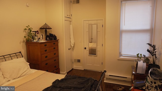 bedroom featuring baseboard heating, multiple windows, visible vents, and dark wood-style flooring