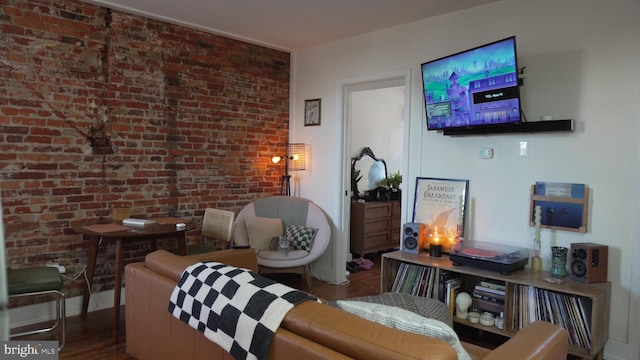 sitting room with brick wall and wood finished floors