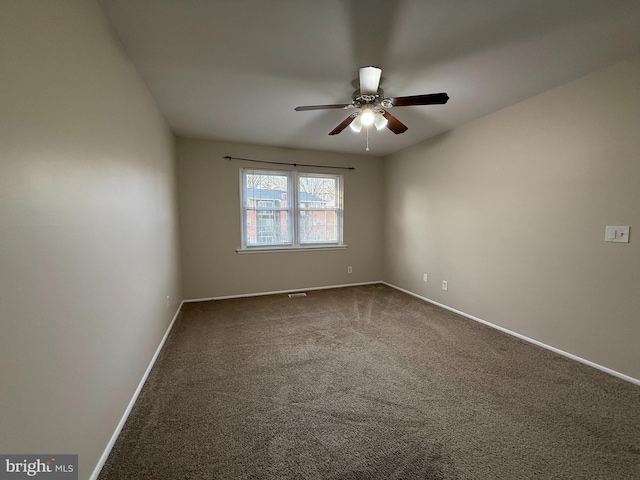 unfurnished room with visible vents, dark carpet, baseboards, and a ceiling fan