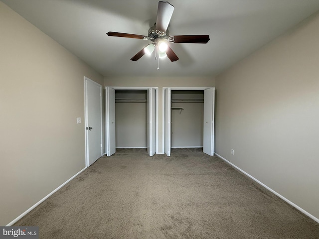 unfurnished bedroom with baseboards, two closets, and carpet