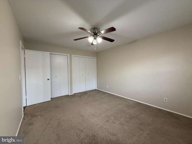 unfurnished bedroom with baseboards, a ceiling fan, multiple closets, and carpet floors