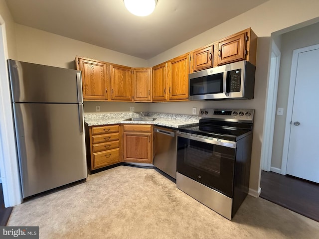 kitchen featuring a sink, stainless steel appliances, light stone countertops, and brown cabinetry