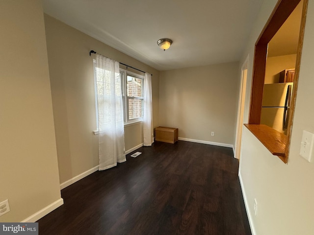 unfurnished dining area featuring visible vents, baseboards, and dark wood finished floors