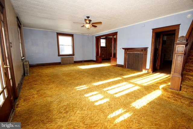 unfurnished living room with ceiling fan, carpet, radiator heating unit, and baseboards