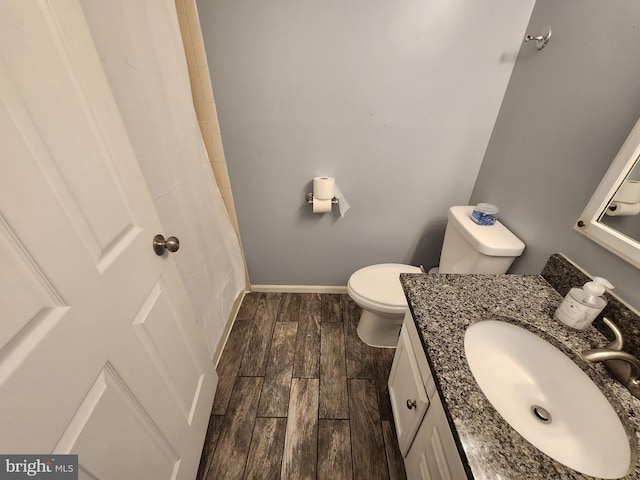 full bathroom with vanity, a shower with shower curtain, baseboards, wood finish floors, and toilet