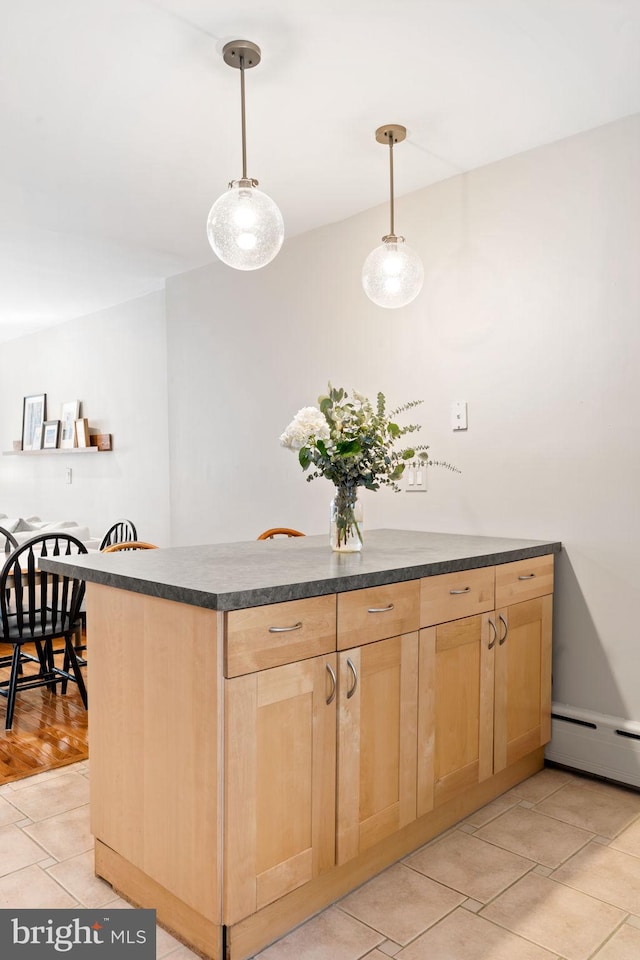 kitchen with dark countertops, light brown cabinetry, decorative light fixtures, light tile patterned floors, and a baseboard radiator