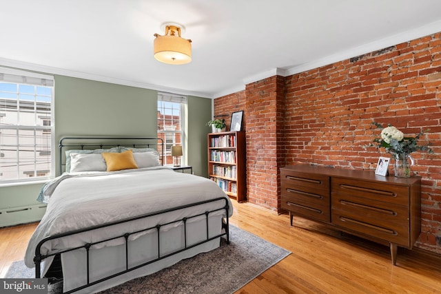 bedroom with a baseboard heating unit, crown molding, light wood-style flooring, and brick wall