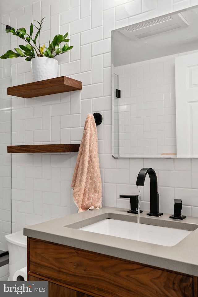 bathroom featuring vanity, tile walls, toilet, and backsplash