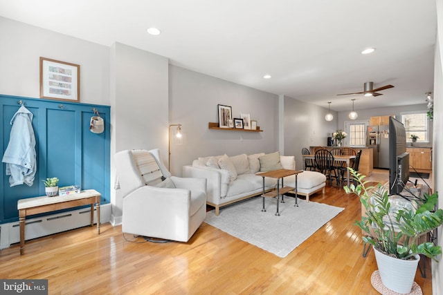 living area with a wainscoted wall, a ceiling fan, recessed lighting, light wood finished floors, and a baseboard radiator