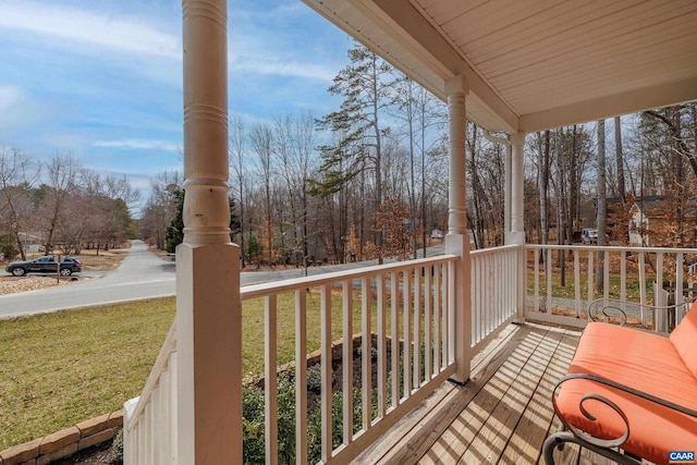 wooden deck featuring a porch and a lawn