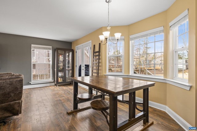 dining area with french doors, baseboards, a notable chandelier, and dark wood finished floors