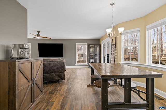 dining space featuring ceiling fan with notable chandelier, visible vents, dark wood-style floors, and baseboards