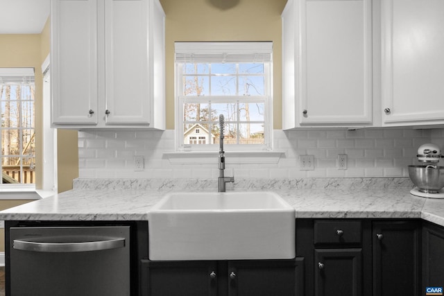 kitchen with a sink, tasteful backsplash, stainless steel dishwasher, and white cabinetry