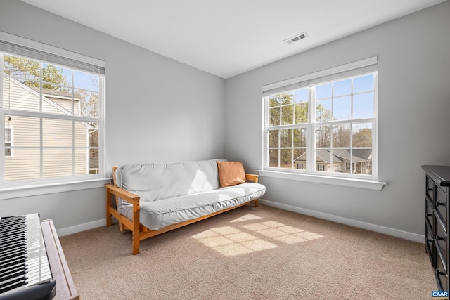 living area featuring a wealth of natural light, baseboards, and carpet flooring