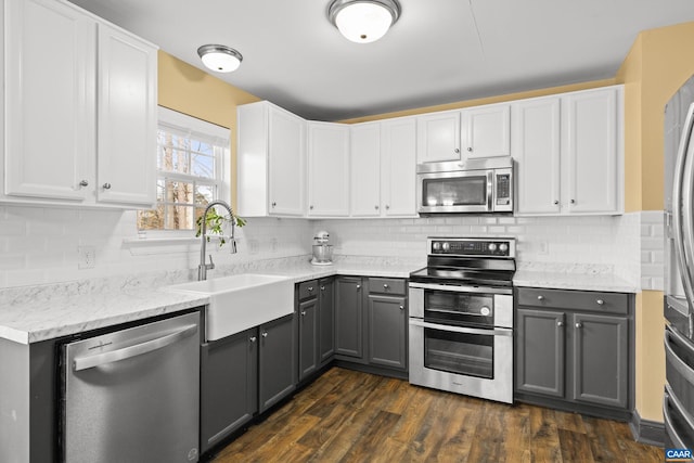 kitchen with dark wood finished floors, gray cabinets, a sink, appliances with stainless steel finishes, and white cabinetry