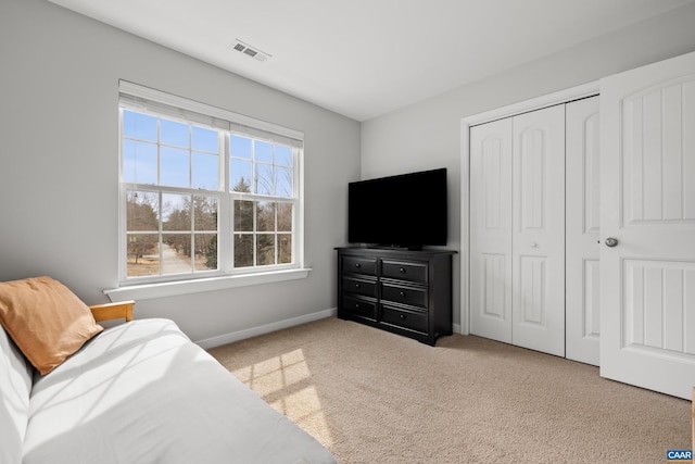 carpeted bedroom with visible vents, baseboards, and a closet