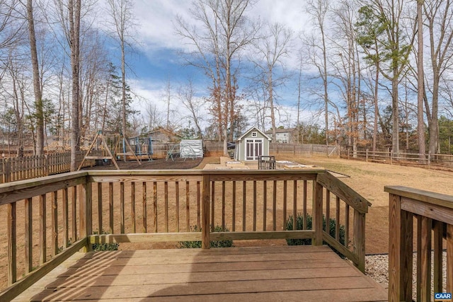 wooden deck with a fenced backyard, a storage shed, an outdoor structure, and a playground