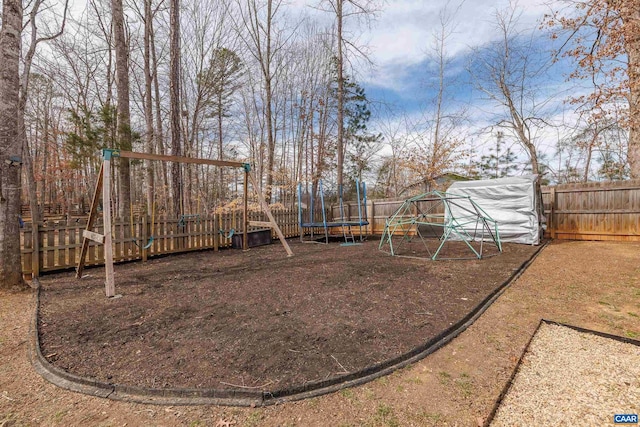 view of yard featuring a playground, a trampoline, and a fenced backyard