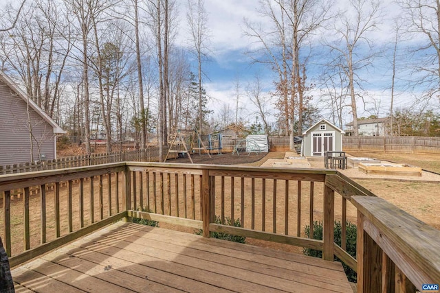 wooden terrace with an outbuilding, a fenced backyard, a storage shed, and a playground