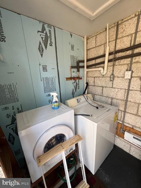 laundry room with washer and clothes dryer, concrete block wall, and a baseboard radiator