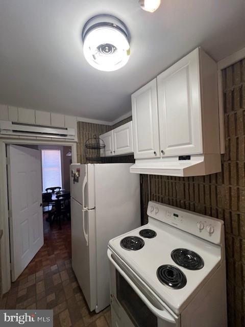 kitchen featuring under cabinet range hood, white appliances, and white cabinets