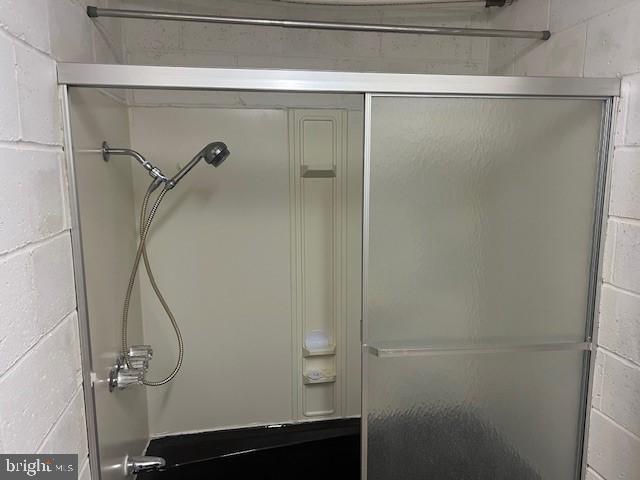 bathroom featuring an enclosed shower and concrete block wall